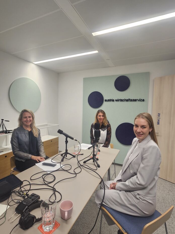 3 Frauen rund um den Tisch mit Podcast-Mikrofon