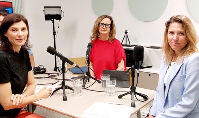 3 Frauen rund um den Tisch mit Podcast-Mikrofon